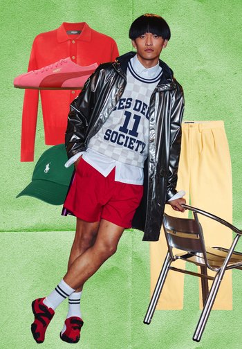 Man draagt glanzende zwarte jas, witte trui met tekst, rode short en rood-zwarte schoenen, leunend op metalen stoel tegen een groene achtergrond.