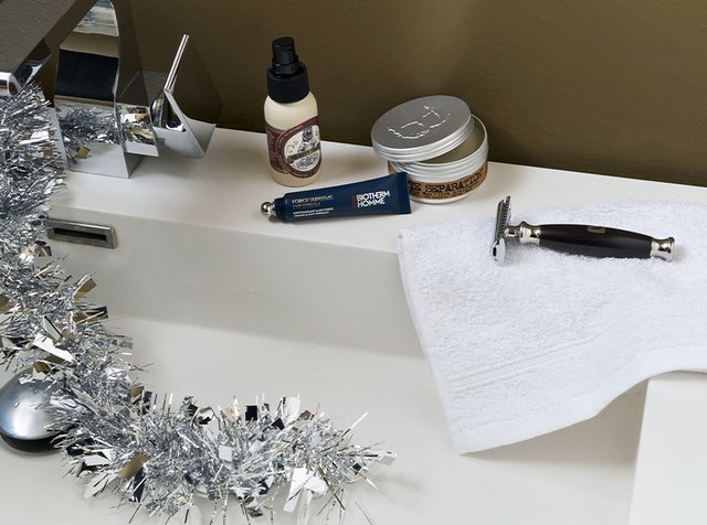 Sølv glitter dekorerer en vaskebenk med barberskum, aftershave-flaske, Biotherm Homme øyekrem, håndkle og sikkerhetsbarberhøvel.