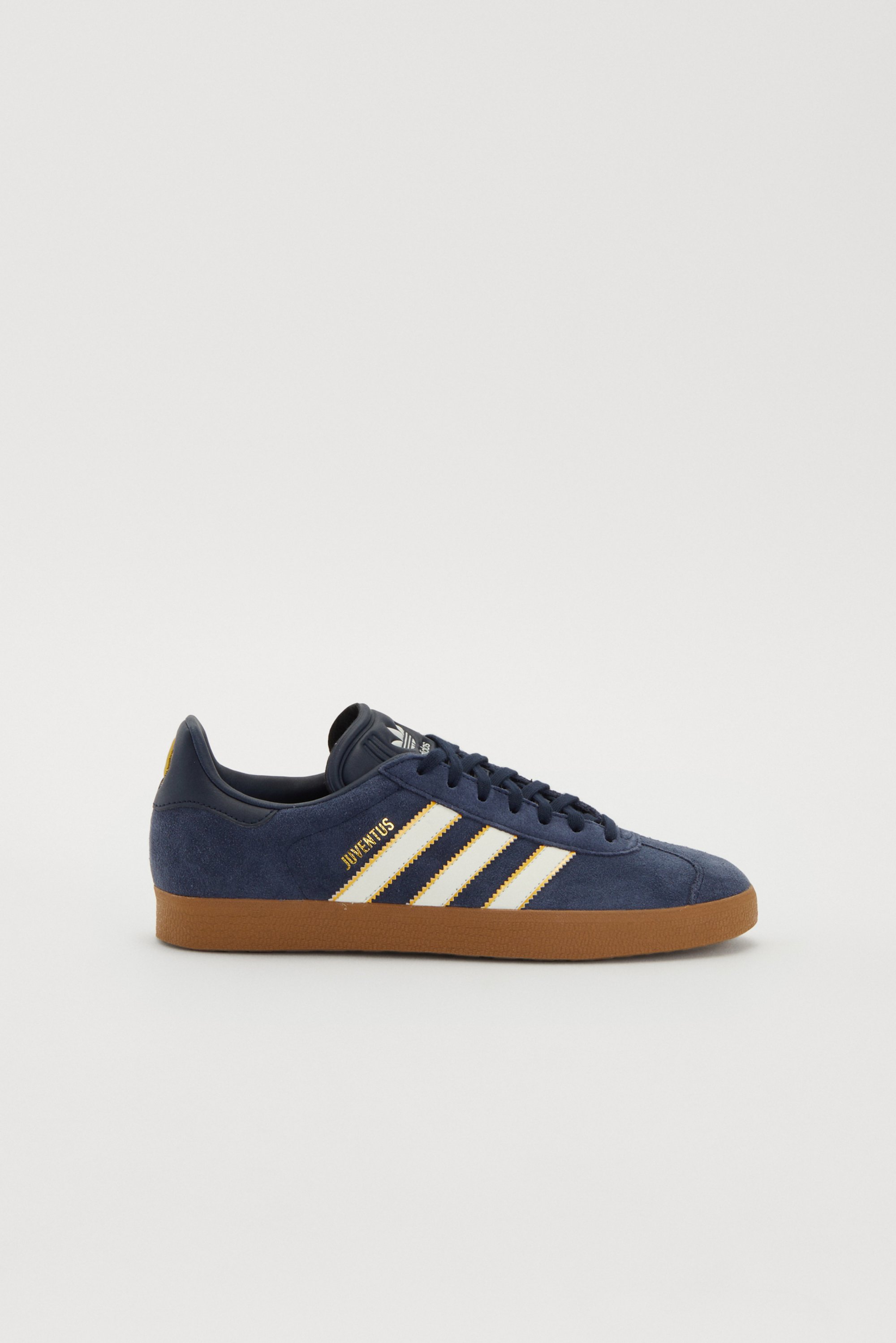 Marineblauwe sneakers met witte en gouden strepen; voorzien van een gumrubber zool en het "JUVENTUS" logo aan de zijkant, tegen een witte achtergrond.
