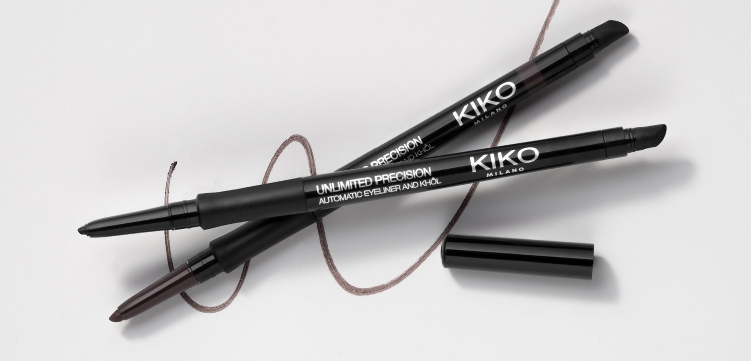 Deux eye-liners automatiques noirs Kiko Milano avec des traits marron dessinés autour d'eux sur une surface blanche, un avec le bouchon retiré.