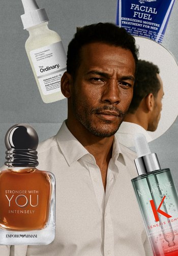 Parfümflaschen und Hautpflegeprodukte neben einem Mann mit weißem Hemd, dunkler Haut und kurzen lockigen Haaren. Der Hintergrund ist gedämpft grau.