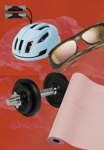 Un casco da ciclismo blu chiaro, occhiali da sole con lenti marroni, un manubrio nero con una maniglia argentata e un tappetino per esercizi rosa sono disposti su uno sfondo rosso.