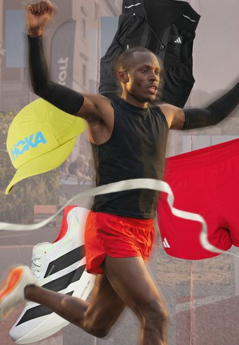 Biegacz przerywa taśmę mety, ubrany w czarny bezrękawnik i czerwone spodenki, otoczony żółtą czapką, czarną kamizelką i białymi butami do biegania.