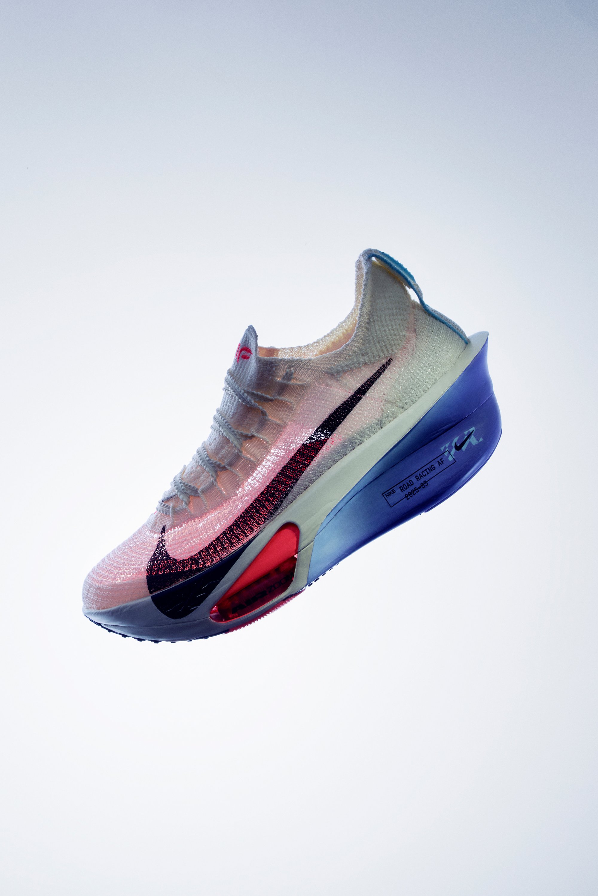La chaussure de course Nike présente un dessus en tricot blanc, un swoosh noir et une semelle multicolore avec des accents rouges et bleus. Design léger et respirant.