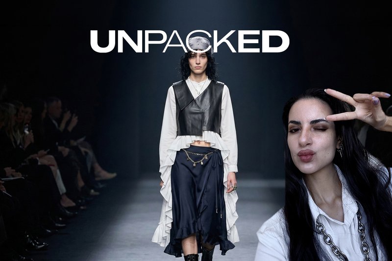 Model läuft auf dem Laufsteg in einer geschichteten schwarzen Lederweste über einer weißen Rüschenbluse und einem marineblauen asymmetrischen Rock; Frau zeigt im Vordergrund das Friedenszeichen.