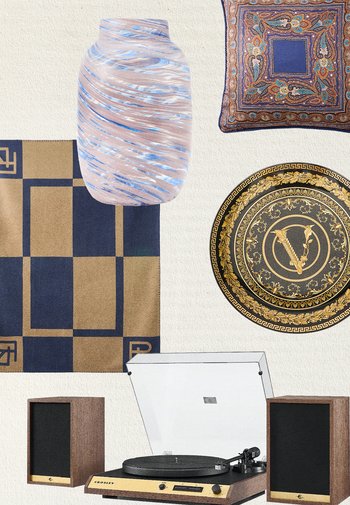 Platine vinyle avec enceintes en bois sous une écharpe à damier bleu et beige, un coussin à motifs bleus et oranges, une assiette décorative noire et dorée, et un vase bleu tourbillonnant.
