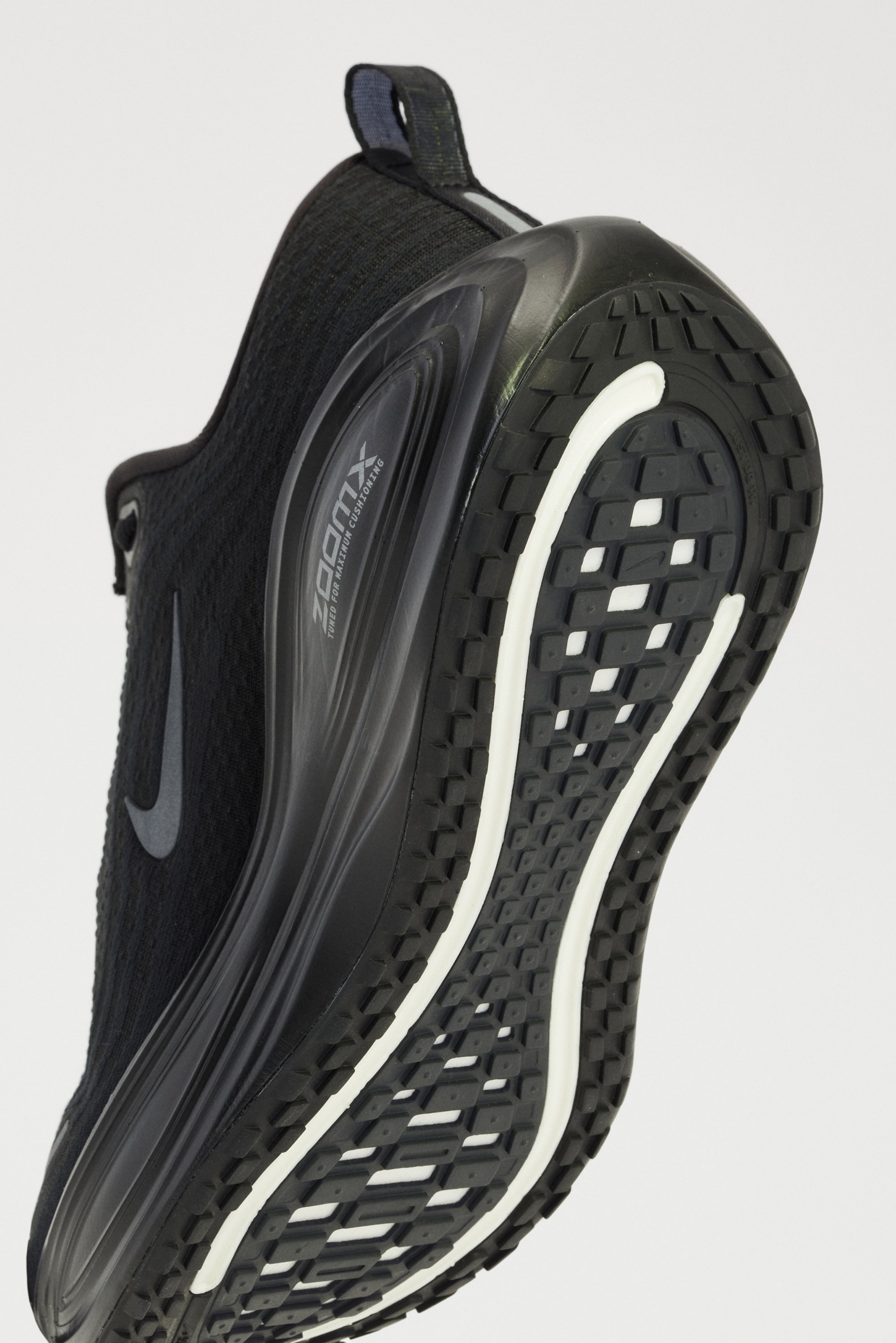 Zwarte sportschoen met een gestructureerde bovenkant, een opvallende Nike swoosh en een rubberen zool met een kenmerkend profiel en witte accenten.