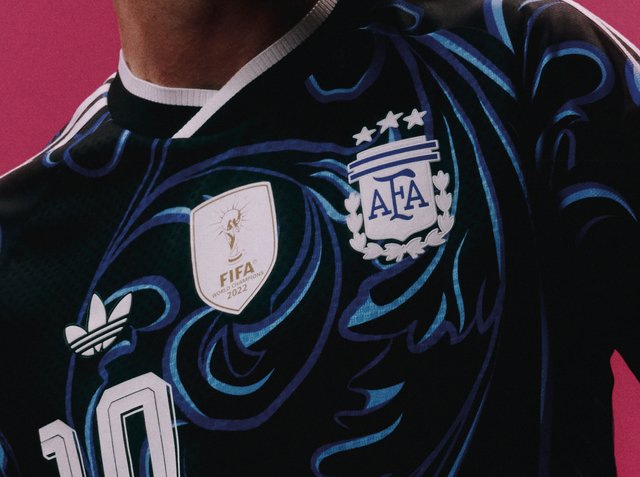 Close-up van een zwart-blauw Argentijns voetbalshirt met het FIFA Wereldkampioen 2022-badge, het AFA-logo, het Adidas-logo en nummer 10.
