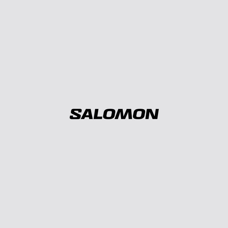 Musta "SALOMON" -logo harmaalla taustalla, edustaen brändiä, joka liittyy ulkoilurientoihin ja vapaa-ajan välineisiin.