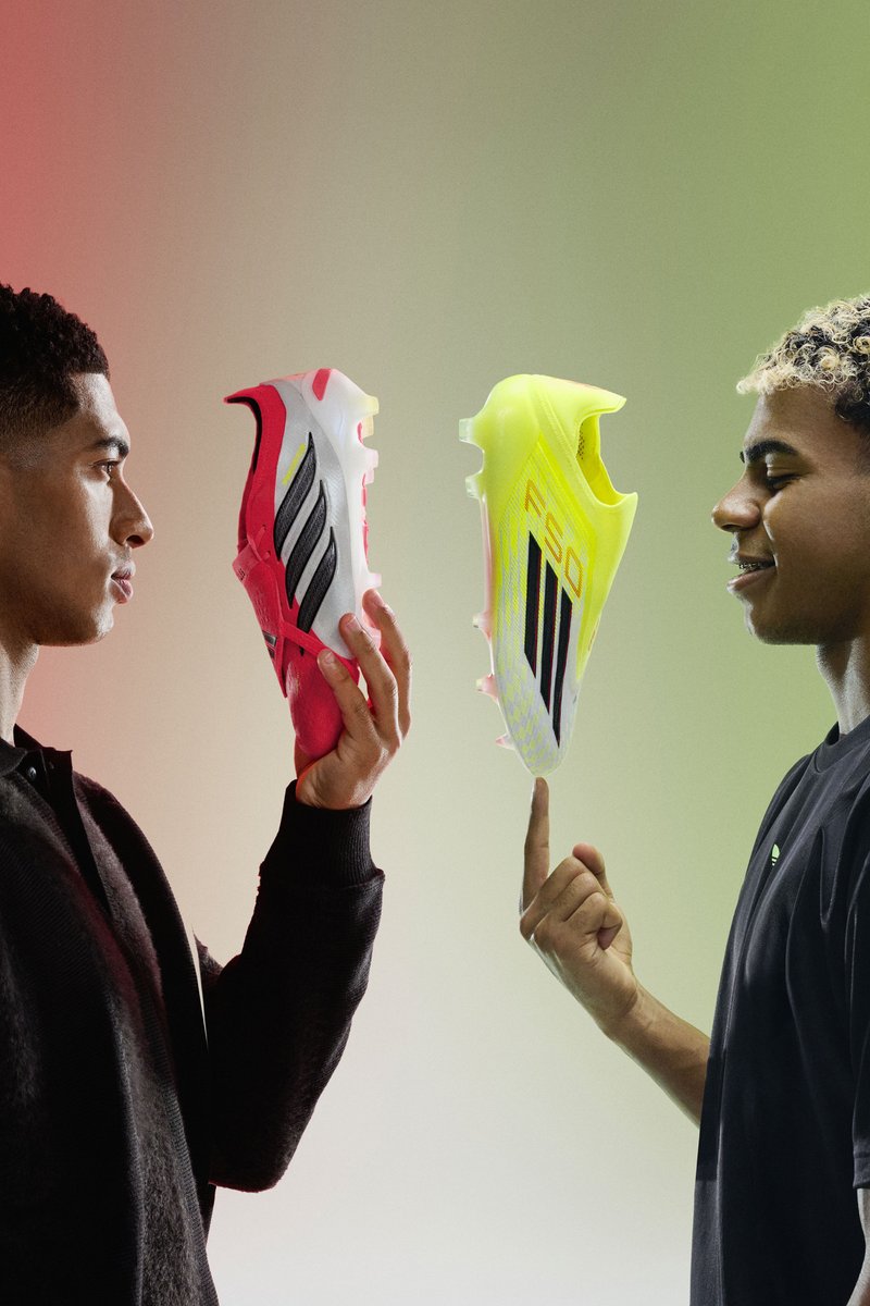 Two men face each other, holding and balancing brightly coloured Adidas football boots, red-white and neon yellow-black, against a gradient background.