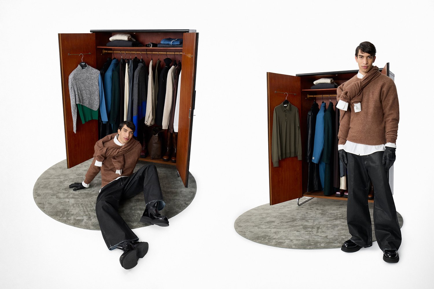 A man sits on the floor beside an open wardrobe filled with various clothing. He wears a brown sweater and gloves, looking at the camera.
