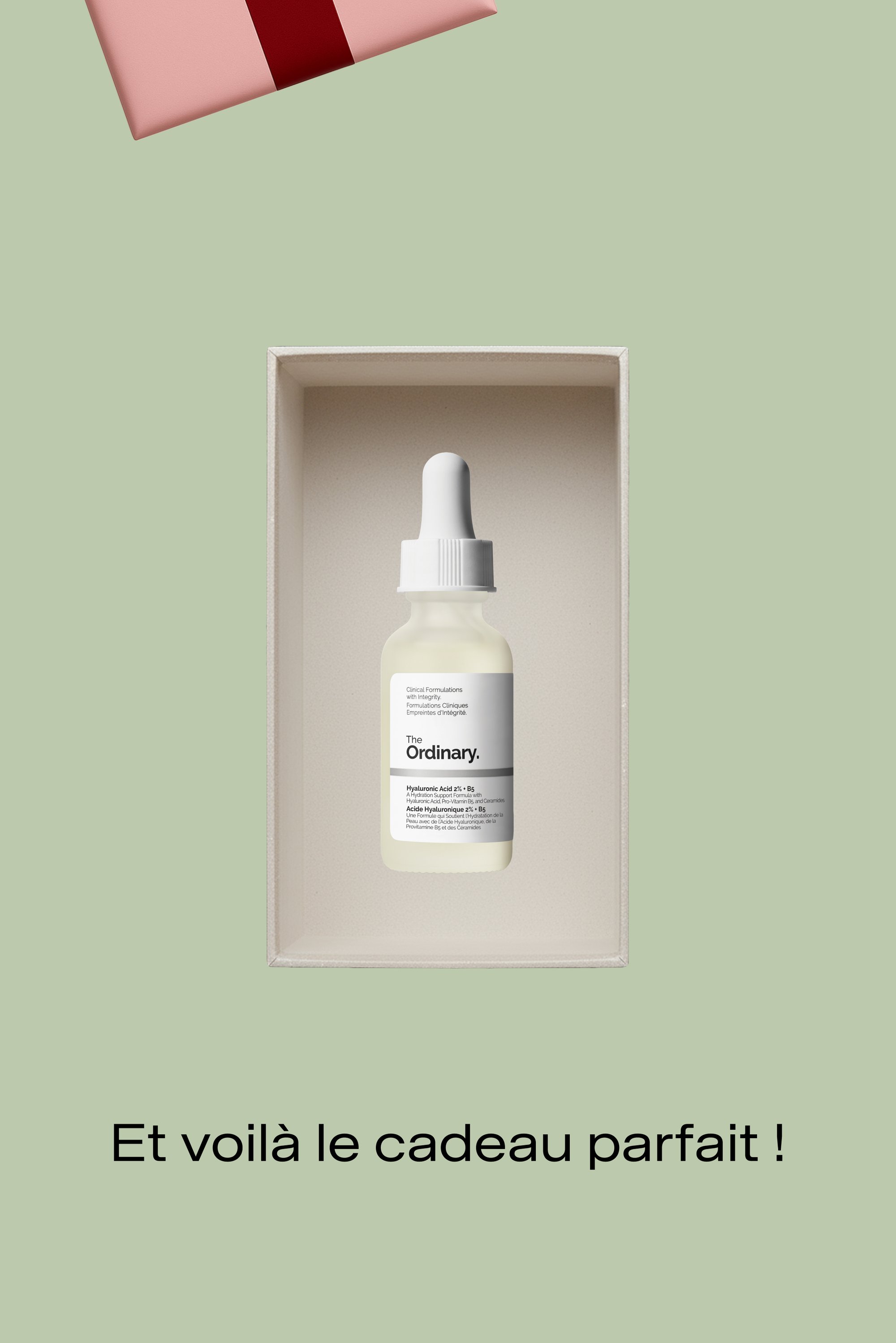 Flacon compte-gouttes en verre transparent étiqueté "The Ordinary", contenant un liquide léger, à l'intérieur d'une boîte beige avec un emballage cadeau rose au-dessus.