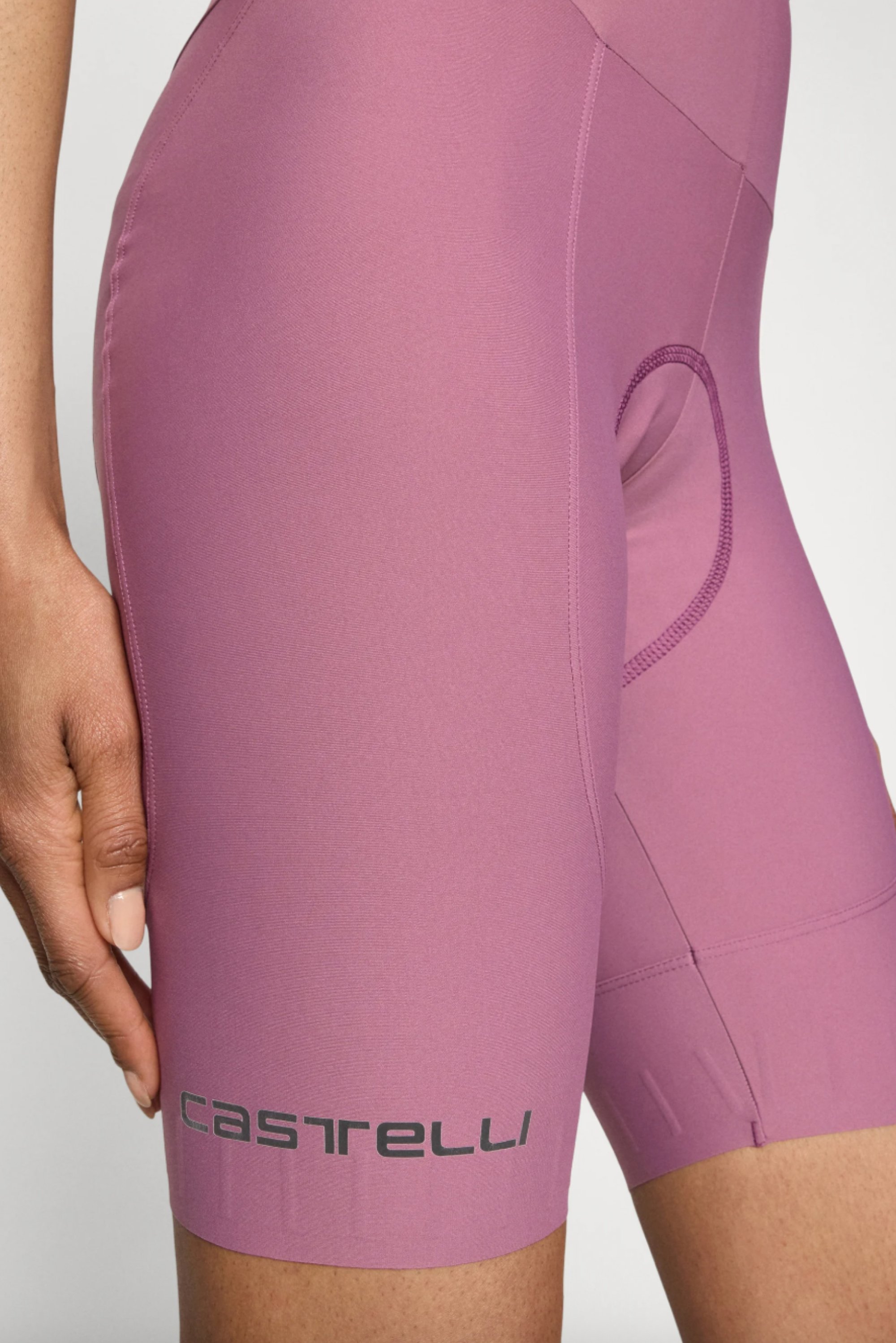 Nahaufnahme des Oberschenkels einer Person in lila Radsportshorts mit dem "Castelli"-Logo am unteren Saum, wobei der Stoff und die Passform hervorgehoben werden.
