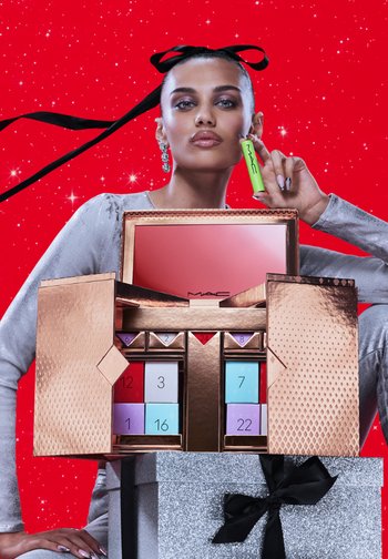 MAC cosmetic gift box with a metallic gold finish and pink interior, featuring colored compartments and a silver gift box with a black ribbon.