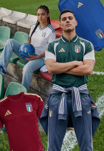 Mann in grünem Italien-Soccer-Polo mit gestreifter Jacke, die um die Taille gebunden ist, steht auf dem Spielfeld; Frau in weißem Italien-Trikot hält blauen Fußball auf den Stadiontribünen.