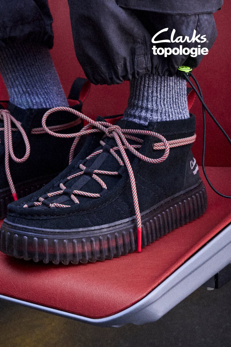 Sorte filtsneakers med en tyk, klar gummisål. Har røde og grå snørebånd samt grå ribbede sokker, placeret på et rødt sæde.