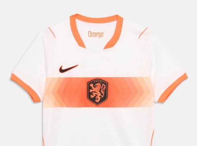 Fehér sportmez narancssárga gallérral és ujjvégekkel, középen narancssárga átmenetes sávval, fekete oroszlán címerrel és fekete Nike logóval.