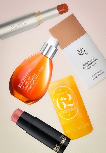 Fem kosmetikprodukter arrangeret fladt: Armani rød læbestift, Biotherm glow serum, tonet solcreme, gul parfume creme og nude læbepomade stift.