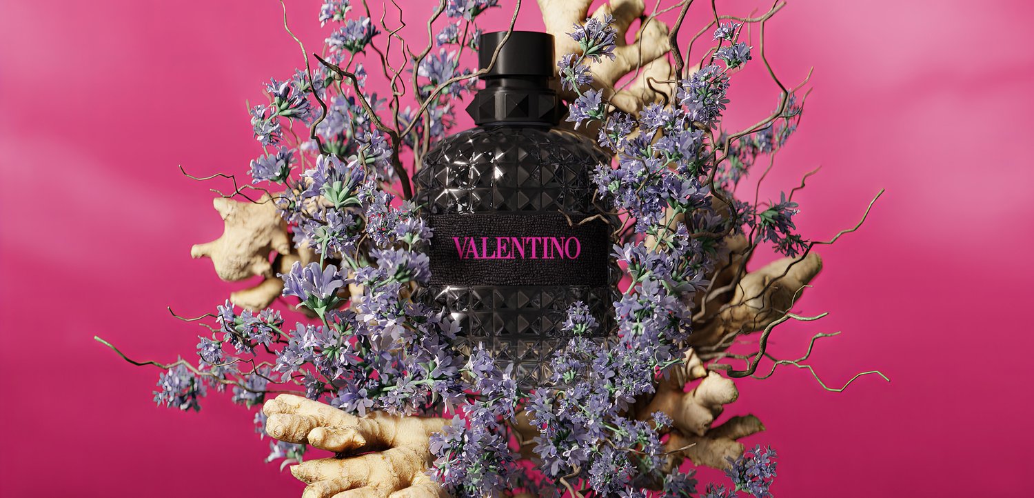 Black Valentino perfume bottle surrounded by purple flowers and beige dried roots against bright pink background.