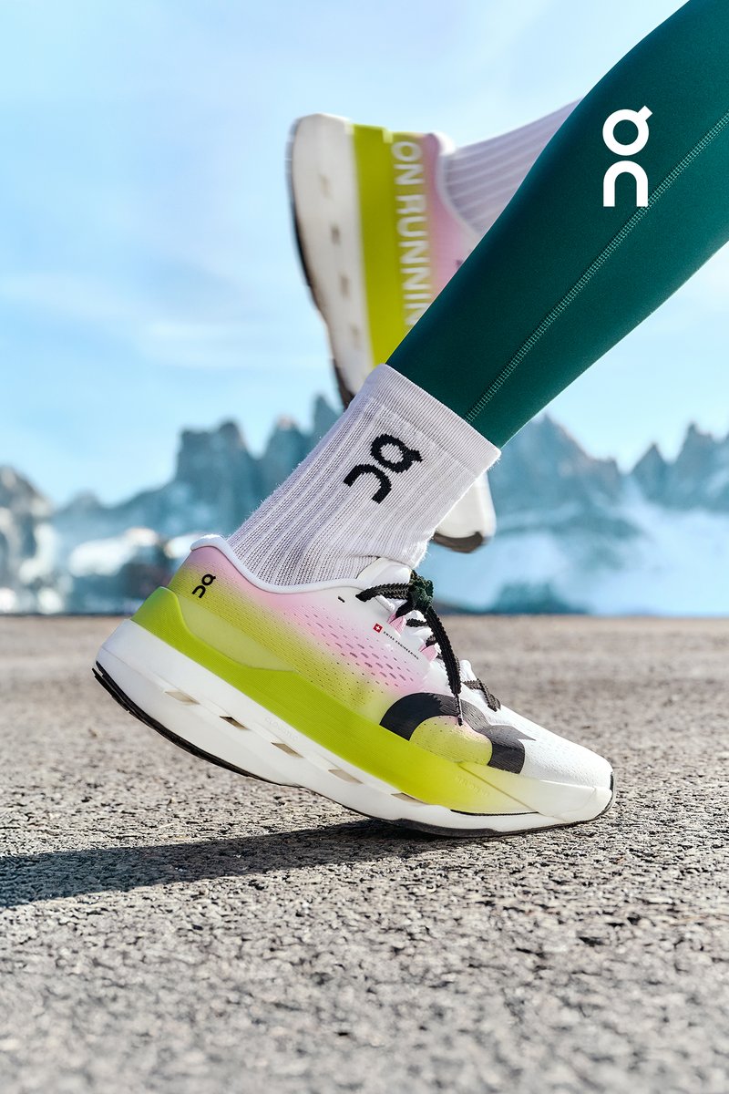 Hardloopschoenen met een wit en neon geel ontwerp, met een verlopende bovenkant van roze naar wit, zwarte accenten en een gestroomlijnde vorm.