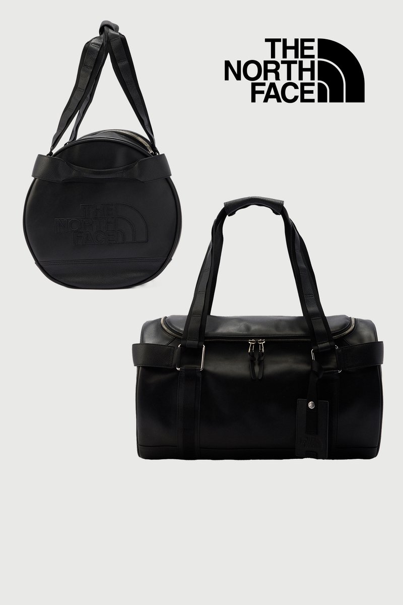 To sorte The North Face-tasker, en rund med dobbelte remme og en rektangulær rejsetaske med lynlås og håndtag på lysegrå baggrund.