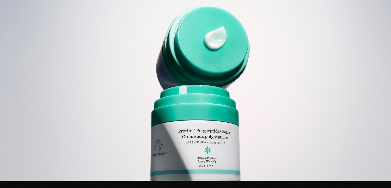 Protini Polypeptide Cream-Glas mit offenem Deckel, auf dem eine kleine Menge Creme zu sehen ist, vor einem schlichten weißen Hintergrund.