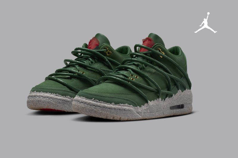 Paar grüne Sneaker mit niedrigem Schaft, grauen strukturierten Sohlen, goldenen Ösen und mehreren sich überlappenden Schnürsenkeln auf grauem Hintergrund.