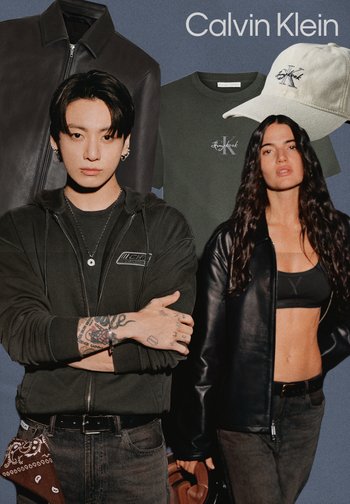 Junger Mann mit Tattoos in schwarzem Hoodie und Frau in schwarzer Lederjacke und Crop-Top stehen vor einer Calvin Klein Lederjacke, Hemd und Cap.