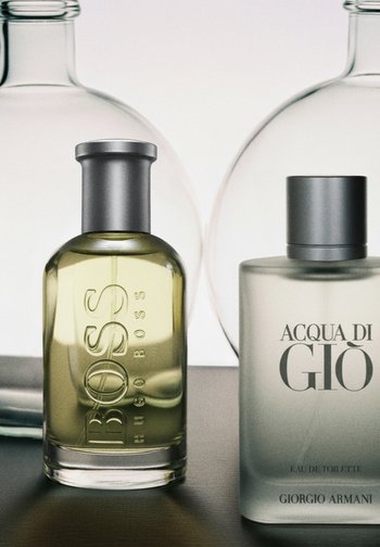 Deux flacons de parfum sur une surface : un flacon translucide jaune de Hugo Boss et un flacon givré d'Acqua di Giò de Giorgio Armani.