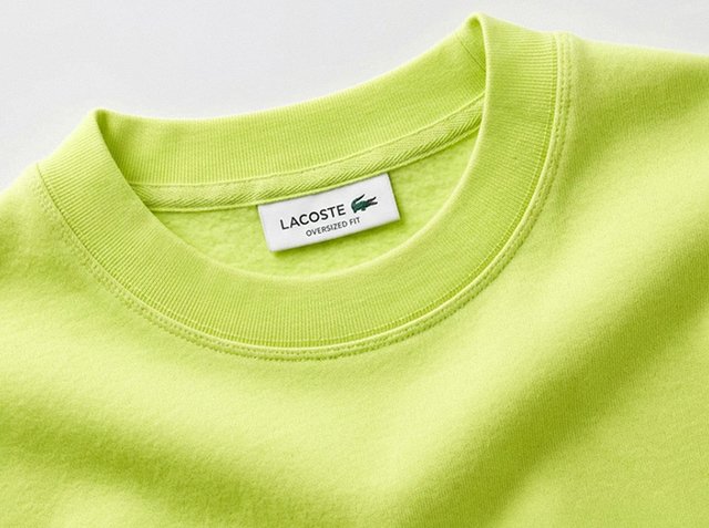 Collo di felpa Lacoste oversize verde chiaro con etichetta del marchio visibile e dettagli di cuciture sul tessuto.