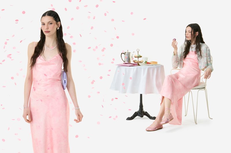 Two women in pink dresses; one stands among falling pink petals, the other sits by a table with tea and pastries.