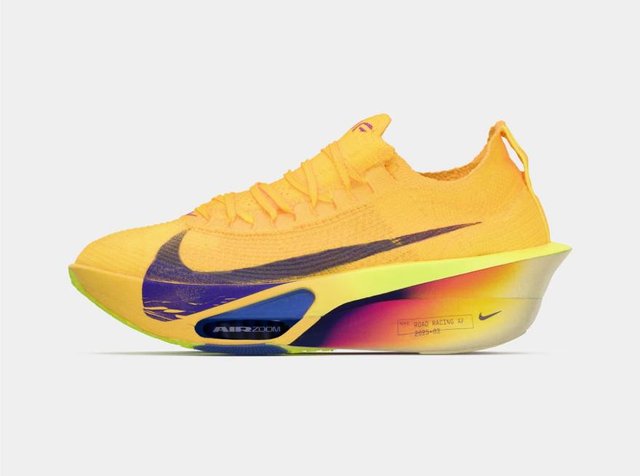 Φωτεινό κίτρινο παπούτσι Nike για τρέξιμο με μοβ σήμα, σόλα με ουράνιο τόξο από κίτρινο σε μοβ και ανυψωμένη φτέρνα για αγωνιστική απόδοση.