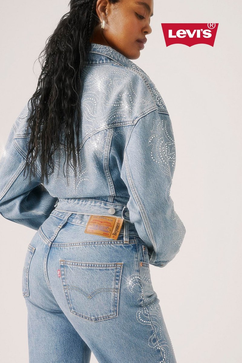 Helles blaues Denim-Jacket und hoch taillierte Jeans, verziert mit silbernen Strasssteinen, klassische Nähte und ein Lederetikett auf der Rückseite.