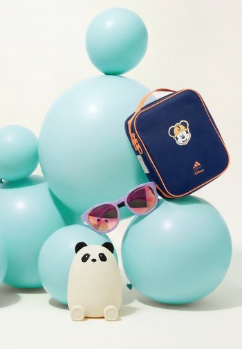 Majhna figurica pande, vijolična sončna očala in mornarsko modra Disneyjeva posedka za malico z oranžnim zadrgo, razporejeni na in okoli velikih turkiznih balonov.