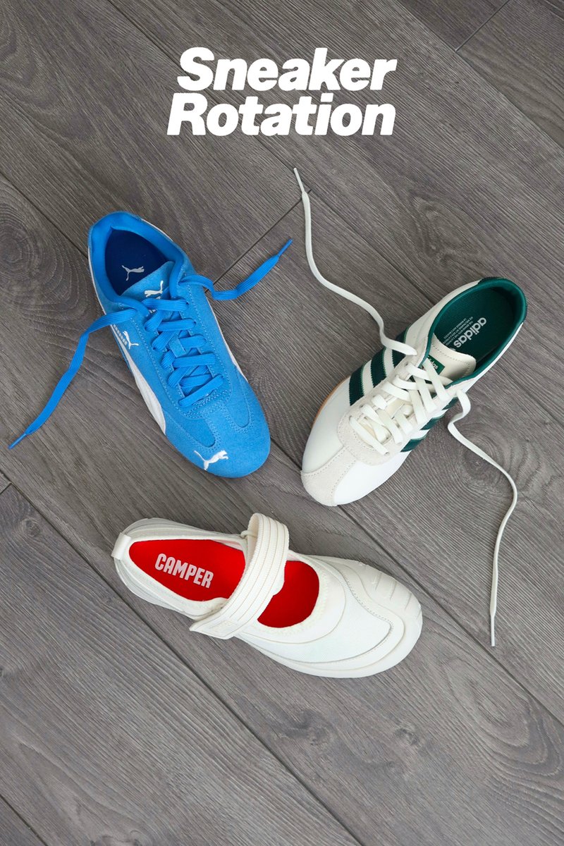 Tre scarpe da ginnastica sono esposte su un pavimento di legno: una Puma blu, una Adidas bianca con righe verdi e una Camper bianca con una soletta rossa.