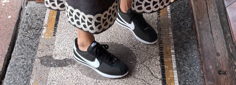 Nere scarpe Nike con dettagli bianchi, materiale testurizzato e lacci, abbinate a una gonna patterned con orlo decorativo.