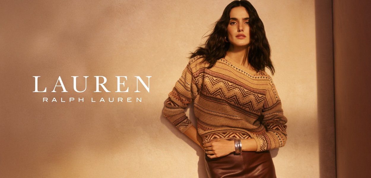 Strikkegenser med geometriske mønstre i beige, brune og røde nyanser; kombinert med et skinnskjørt. Modellen poserer mot en teksturert bakgrunn.