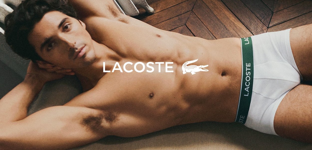 Boxer da uomo Lacoste bianchi in cotone con elastico verde in vita, con il nome e il logo del marchio ben visibili sul davanti.