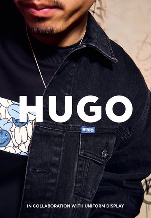 Black denim jacket featuring a blue "HUGO" label, paired with a patterned top displaying light blue and white accents. Close-up view.