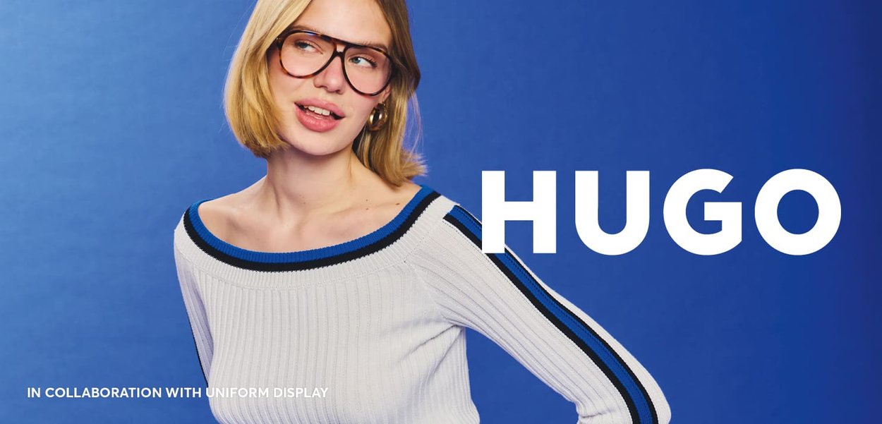 Knitted white sweater with blue accents and wide neckline. Model wears large black glasses, set against a blue background. Text "HUGO" in bold.