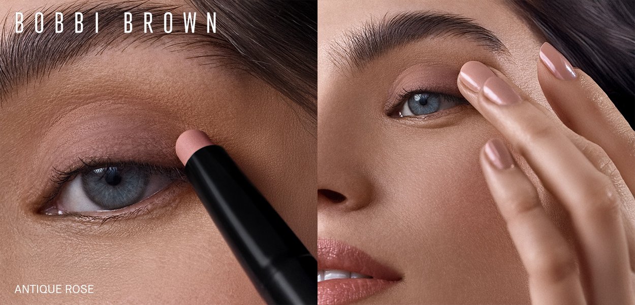 Crayon à ombre à paupières Antique Rose de Bobbi Brown, rose doux, appliqué sur la paupière ; modèle avec un maquillage naturel, ongles rose clair et détail de peau texturée.