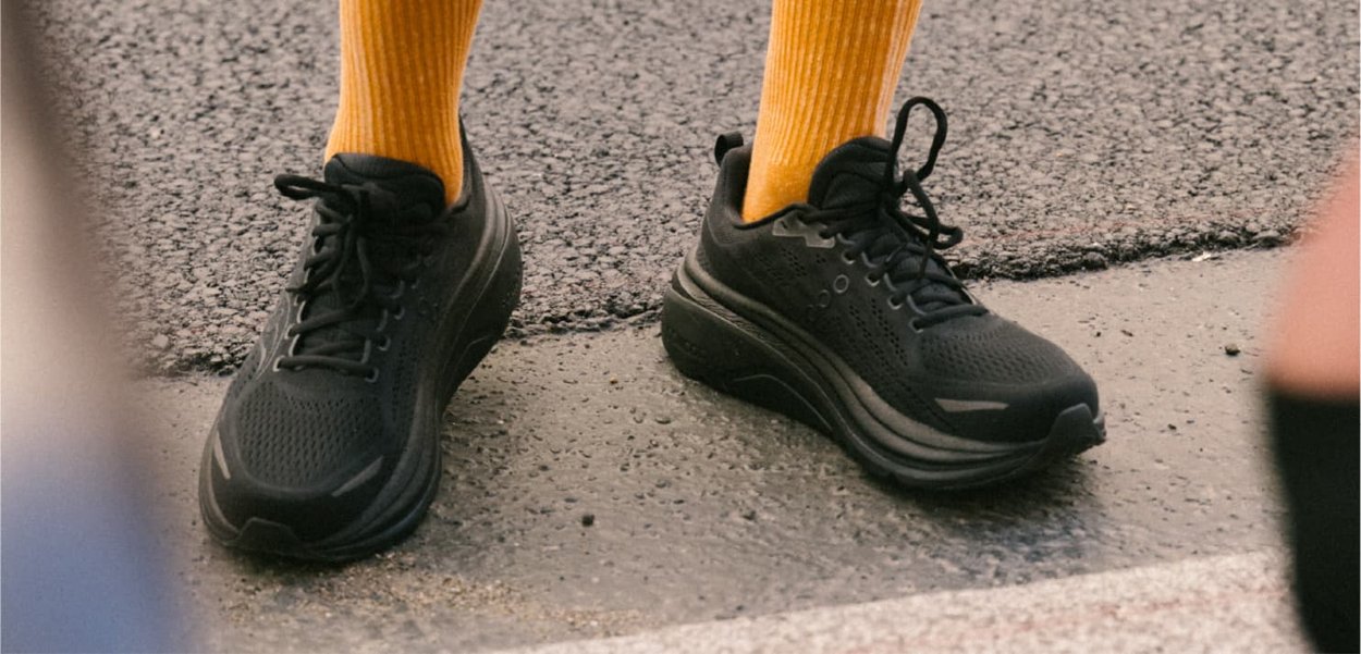Black athletic shoes with a textured upper, featuring laces and a cushioned sole, paired with bright yellow ribbed socks.
