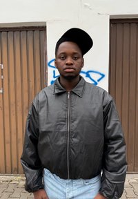 Zwarte, met een rits gesloten bomberjack met een glanzende textuur en een oversized, doorhangende kraag. Draagt bijpassende blauwe jeans met hoge taille.