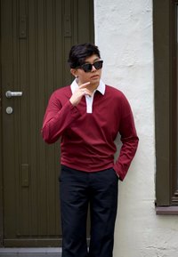 Cămașă polo lungă, bordo, cu guler alb, asociată cu pantaloni negri. Designul este de tip relaxed-fit, având detalii subtile de cusătură.