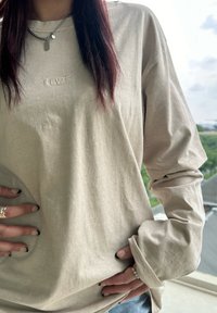 Lichtbeige langslim shirt met subtiele Levi's logo, gemaakt van zachte stof, met een relaxte pasvorm en gecrepeerde mouwen.