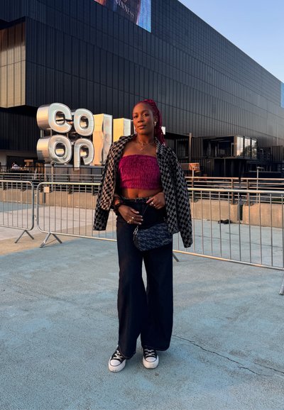 Chaqueta de cuadros en blanco y negro de diseño oversize sobre un top corto esponjoso rosa, combinada con jeans oscuros de pierna ancha y zapatillas negras. Pequeño bolso cruzado.