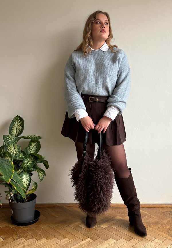 Šviesiai mėlynas megztinis, baltos spalvos marškiniai su apykakle, ruda detalėta sijonas, rudi aukšti batai virš kelių ir ruda kailinė rankinė.