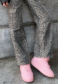 Leopardprint cargobroeken met zijzakken, gecombineerd met lichtroze sneakers met een gladde textuur en vetersluiting.