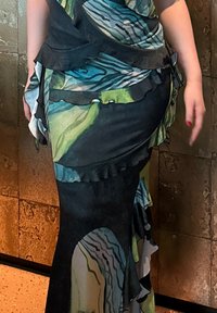 Vestido largo con estampado abstracto en tonos azules y verdes, con volantes a lo largo de los bordes y una silueta ajustada. Fabricado con un material ligero y fluido.