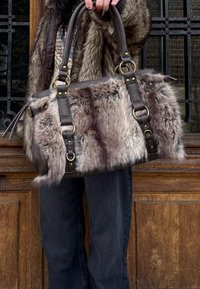 Borsa in pelliccia sintetica con manici e dettagli in pelle marrone, forma rettangolare e componenti metallici. Texture morbida con motivo screziato.